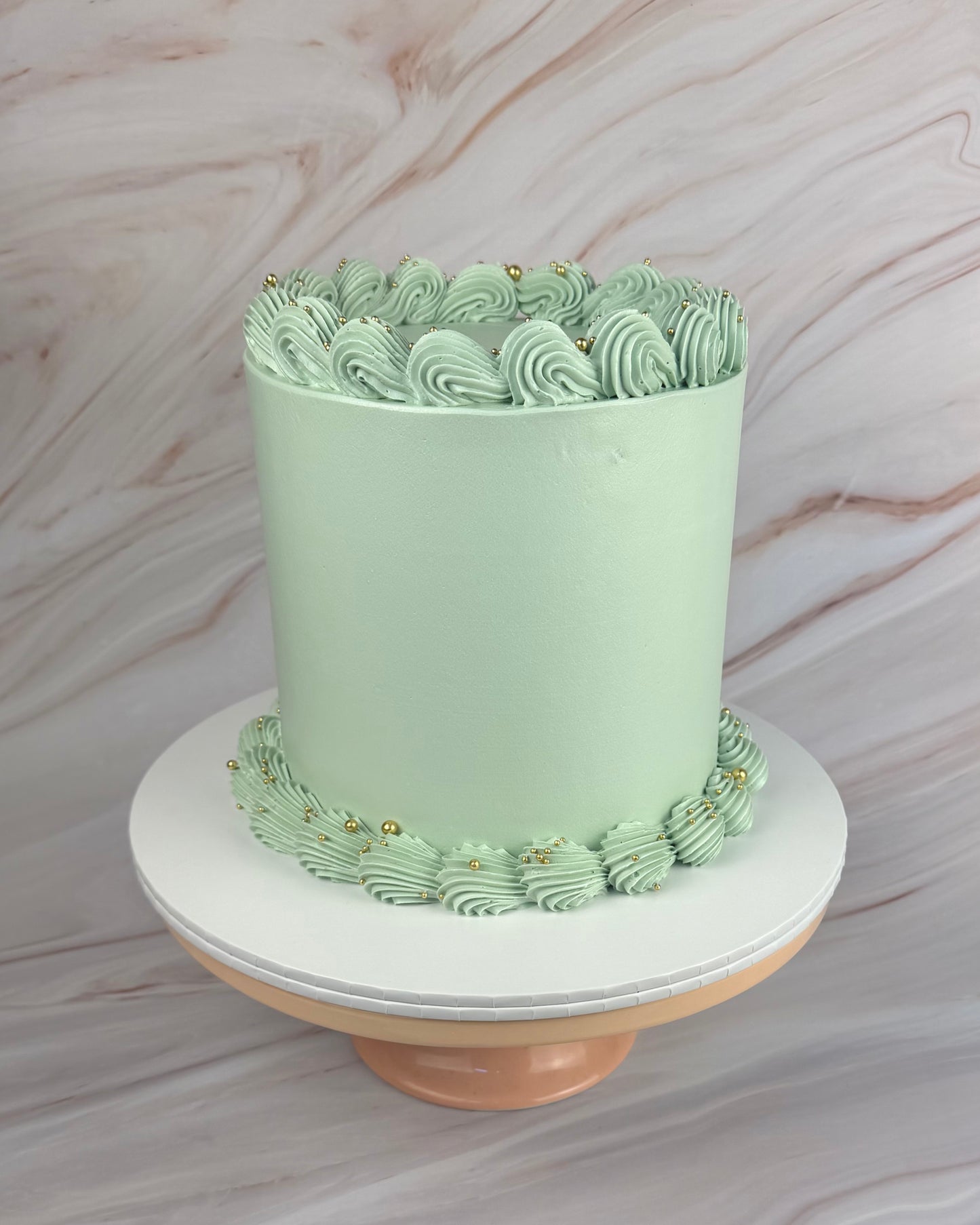 Green cake with decorative swirls on a marble background