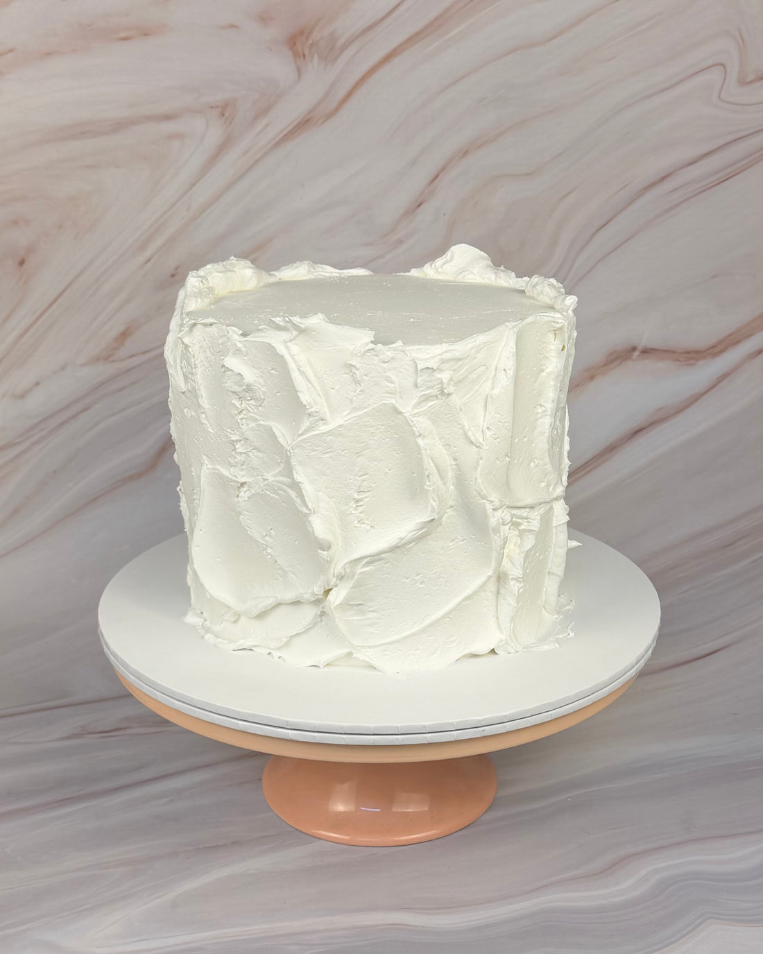 A white round cake with a textured messy buttercream finish